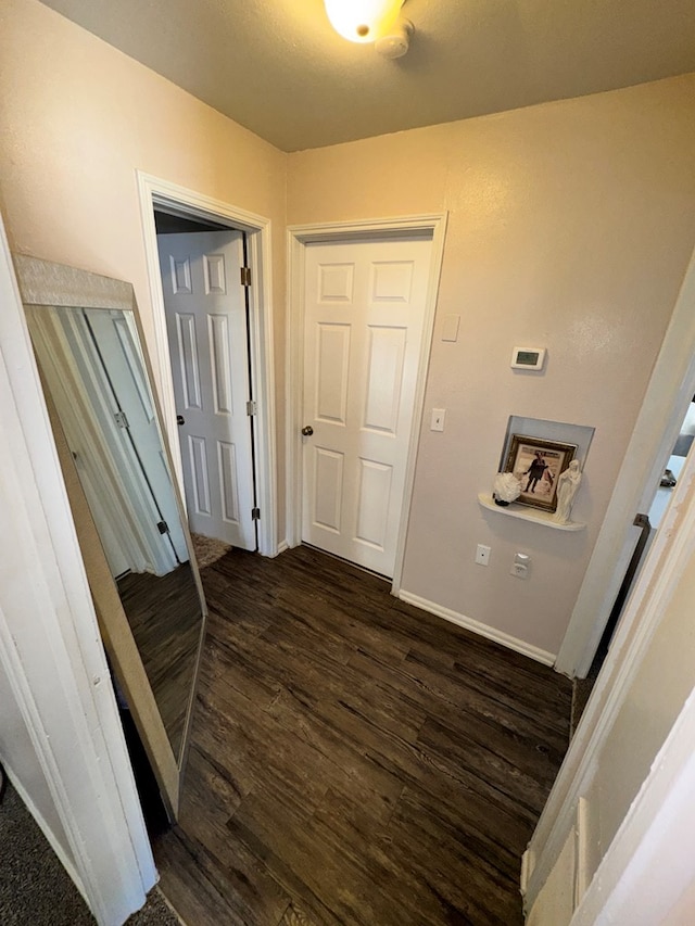 hallway featuring baseboards and dark wood-style flooring