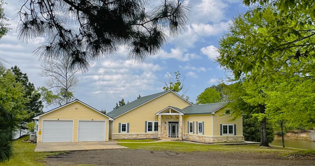 320 Nine Mile Rd, Milam, TX 75959 - view of front of home with driveway, a front yard, and stone siding
