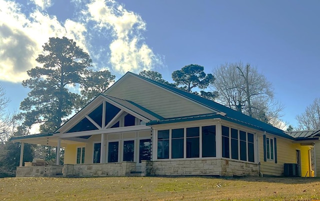 view of home's exterior featuring a yard, central AC unit, and a sunroom