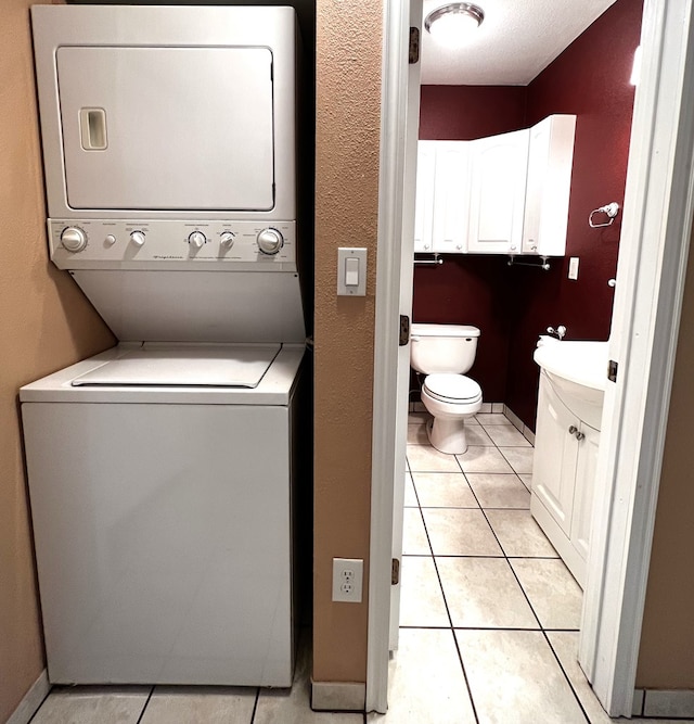 washroom with light tile patterned floors, sink, and stacked washer / dryer