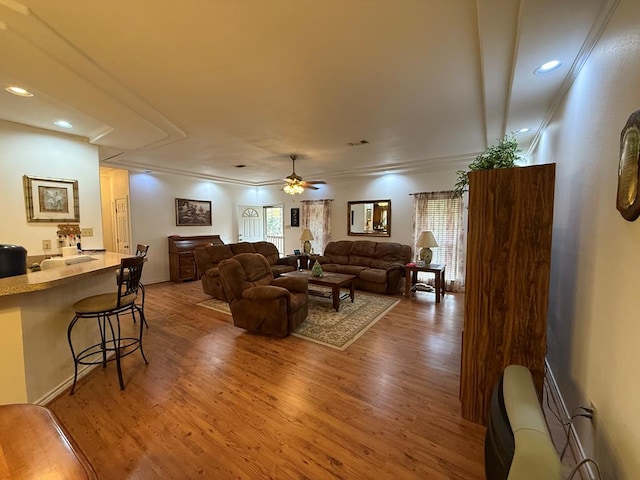 living room featuring ceiling fan, wood-type flooring, and ornamental molding