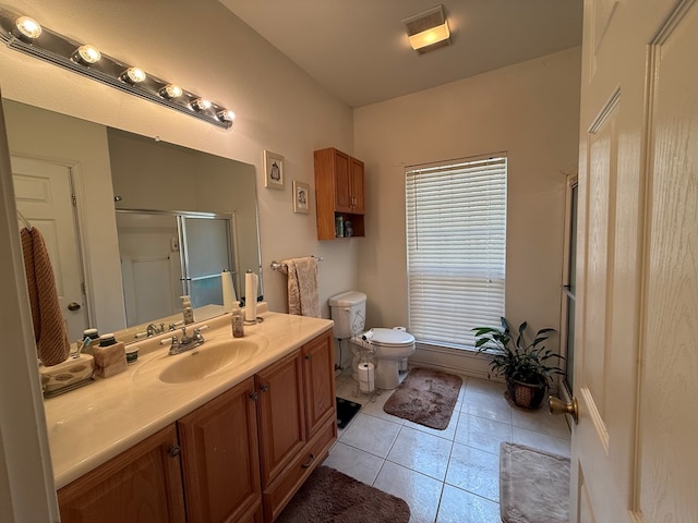 bathroom with toilet, vanity, tile patterned floors, and a shower with shower door