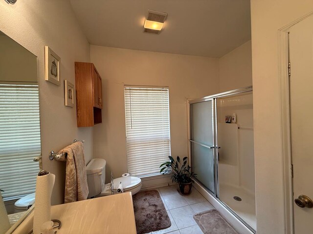 bathroom with tile patterned flooring, vanity, a shower with shower door, and toilet