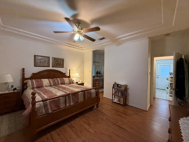 bedroom featuring ceiling fan, hardwood / wood-style floors, ensuite bathroom, and ornamental molding