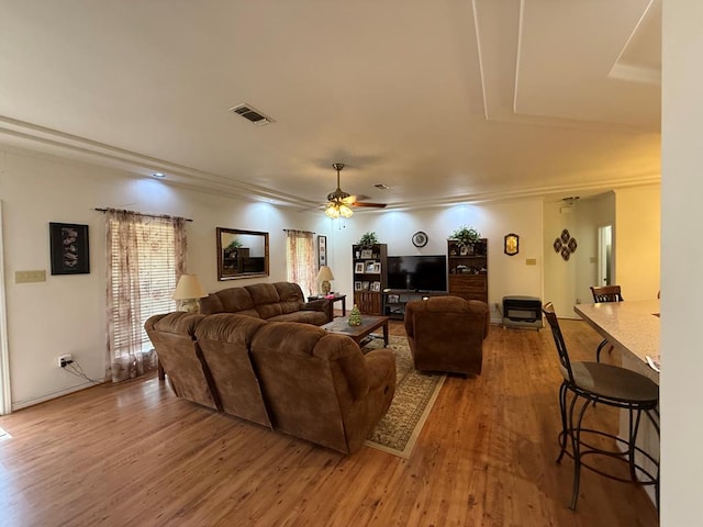 living room featuring ceiling fan, wood-type flooring, and ornamental molding