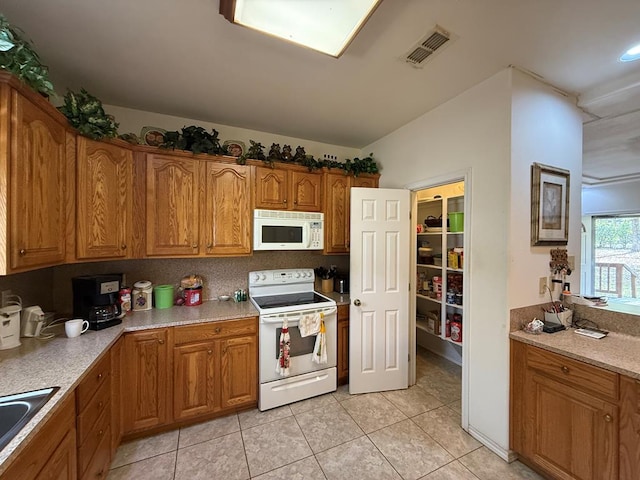 kitchen with light tile patterned floors, white appliances, and sink