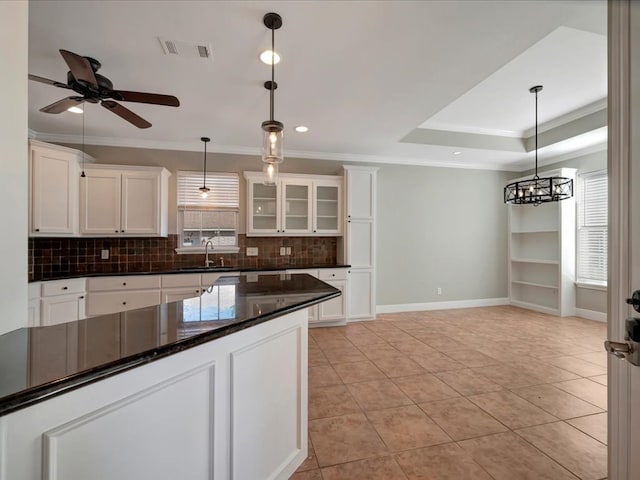 kitchen with a tray ceiling, ceiling fan, pendant lighting, white cabinets, and light tile patterned flooring