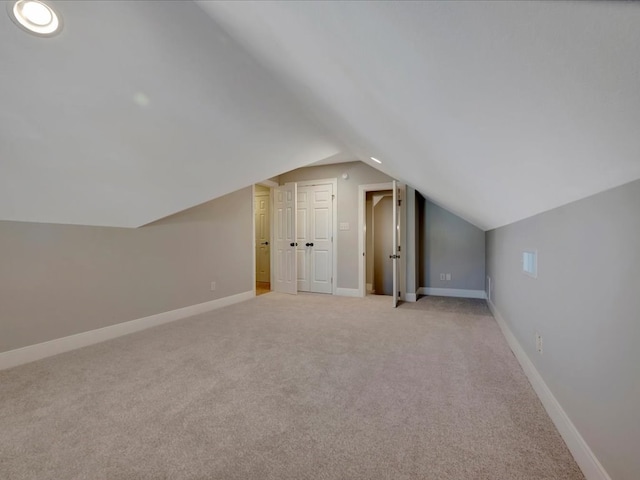 additional living space with light colored carpet and vaulted ceiling