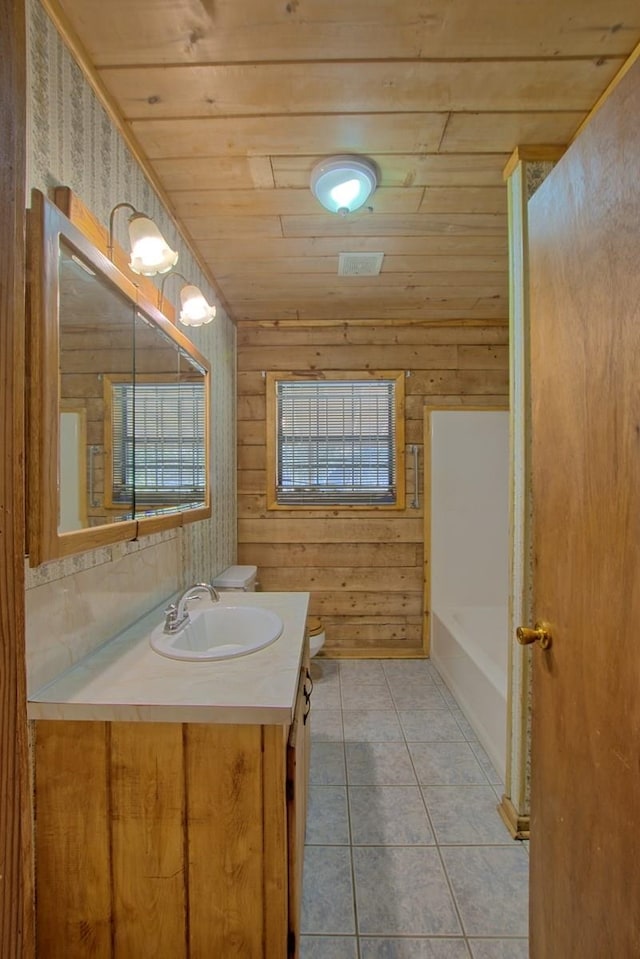 full bathroom with a tub to relax in, toilet, vanity, wooden ceiling, and tile patterned floors