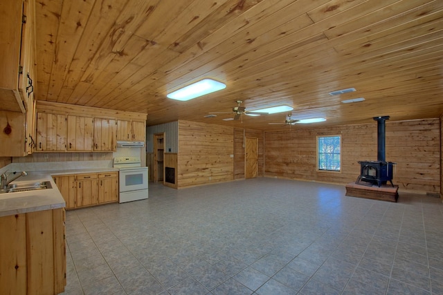 kitchen with light brown cabinets, a sink, light countertops, white range with electric cooktop, and a wood stove