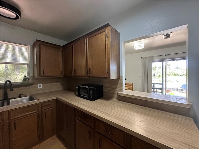 kitchen featuring sink, backsplash, plenty of natural light, and dark brown cabinets