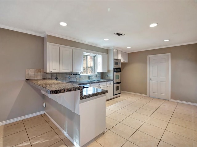 kitchen with white cabinets, appliances with stainless steel finishes, kitchen peninsula, and light tile patterned floors