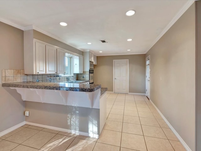 kitchen featuring backsplash, crown molding, light tile patterned floors, kitchen peninsula, and stainless steel appliances