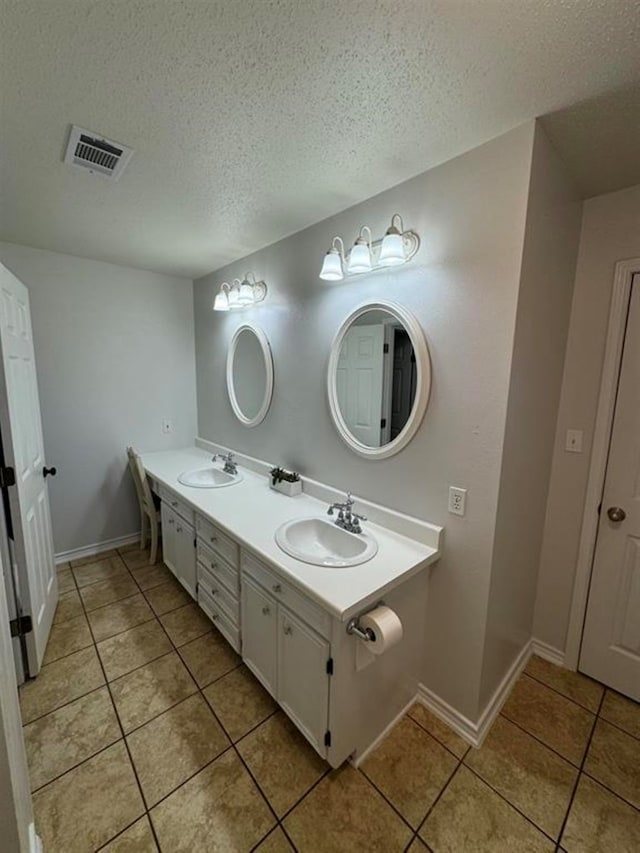 bathroom with tile patterned flooring, vanity, and a textured ceiling