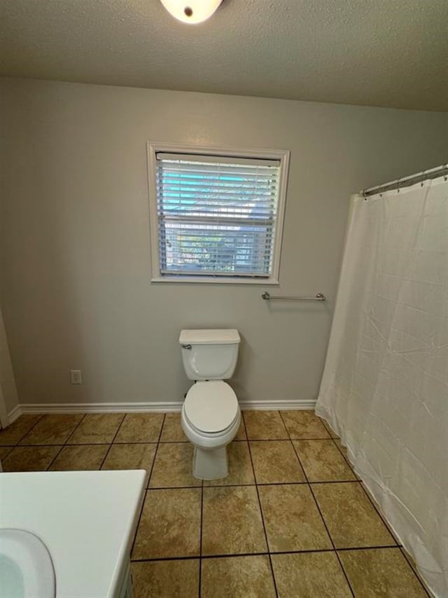 bathroom with tile patterned floors, sink, a textured ceiling, and toilet