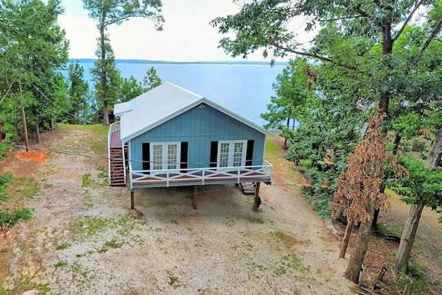 view of front of property featuring french doors, a water view, and stairway