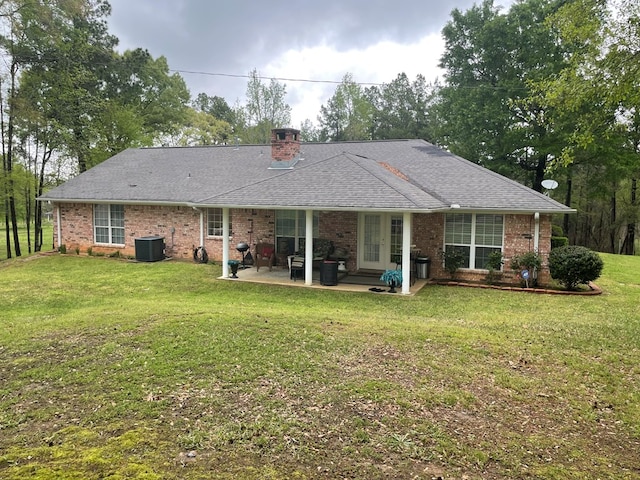 rear view of house with central AC, a patio area, and a lawn