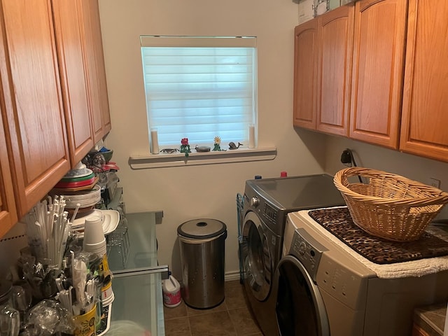 laundry area featuring cabinets, dark tile patterned flooring, and washing machine and clothes dryer