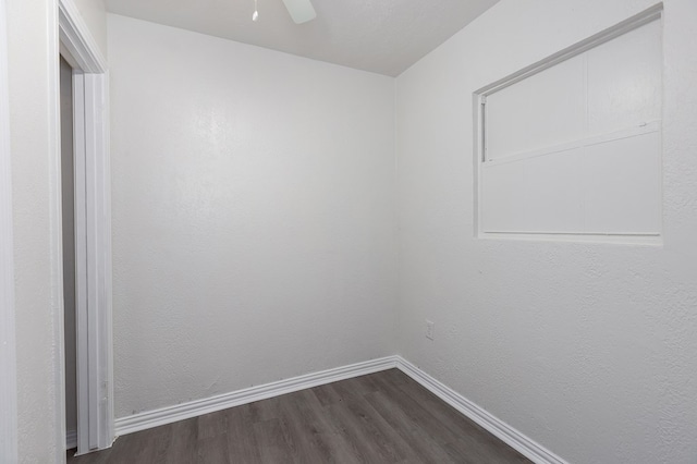 spare room with dark wood finished floors, a ceiling fan, and baseboards