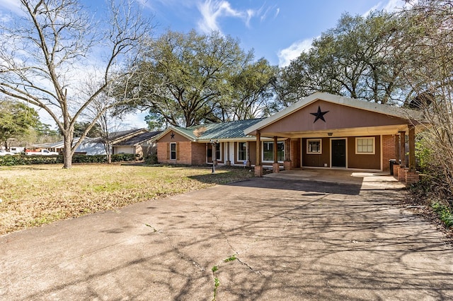 ranch-style home featuring metal roof, brick siding, driveway, a carport, and a front lawn