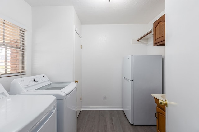 clothes washing area featuring a textured ceiling, separate washer and dryer, wood finished floors, baseboards, and cabinet space