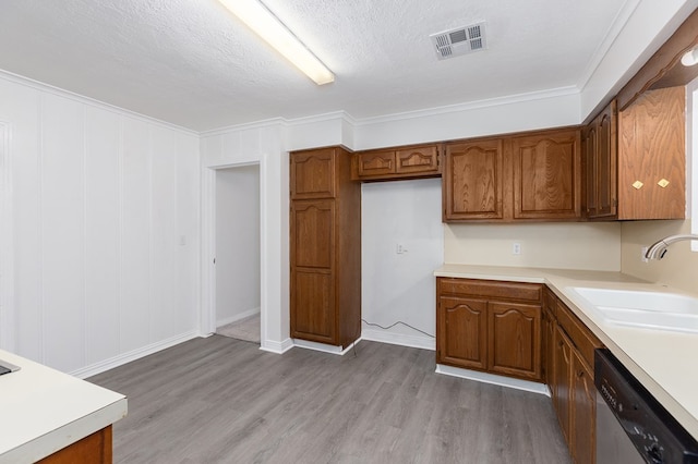 kitchen featuring brown cabinetry, visible vents, a sink, and stainless steel dishwasher