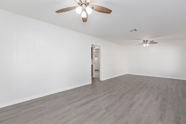 spare room featuring baseboards, visible vents, ceiling fan, and wood finished floors