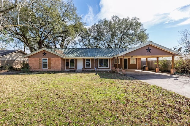 ranch-style house featuring brick siding, a front yard, fence, a carport, and driveway