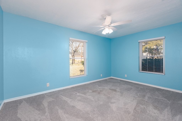 carpeted spare room with baseboards and a ceiling fan