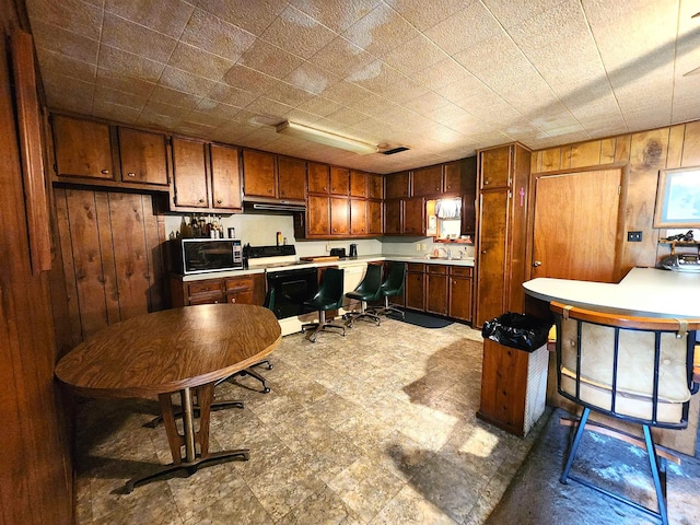 kitchen featuring electric range, wood walls, and sink