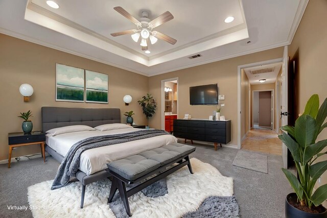 unfurnished bedroom featuring ceiling fan, ensuite bathroom, a tray ceiling, light carpet, and ornamental molding