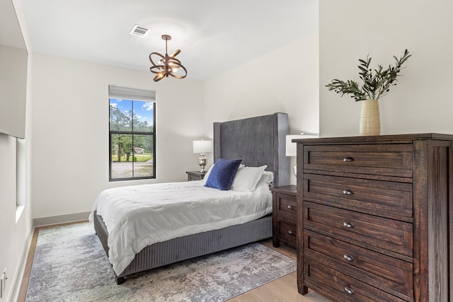 bedroom with baseboards, visible vents, an inviting chandelier, and wood finished floors