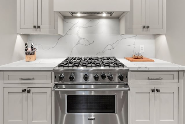 kitchen with decorative backsplash, luxury range, premium range hood, and light stone countertops