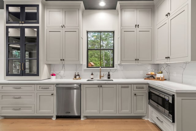 kitchen featuring a sink, decorative backsplash, appliances with stainless steel finishes, and light wood finished floors