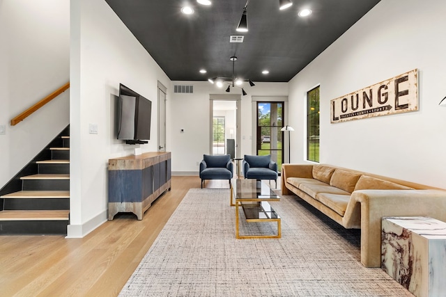 living room featuring visible vents, stairs, wood finished floors, baseboards, and recessed lighting