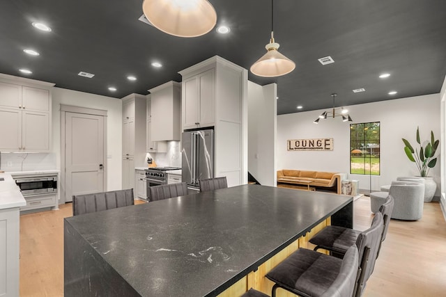 kitchen featuring recessed lighting, open floor plan, high end appliances, light wood-type flooring, and visible vents