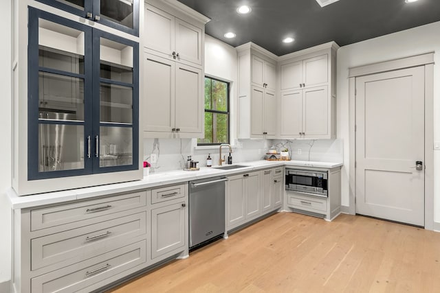 kitchen featuring recessed lighting, a sink, light wood-style flooring, appliances with stainless steel finishes, and backsplash