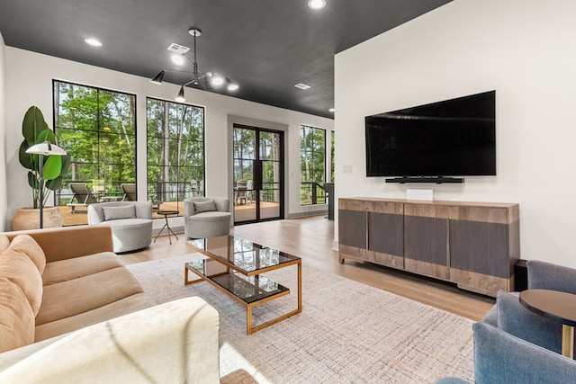 living room featuring visible vents, light wood finished floors, and a wealth of natural light