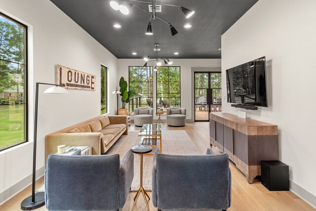 living area with baseboards, a notable chandelier, light wood-type flooring, and visible vents
