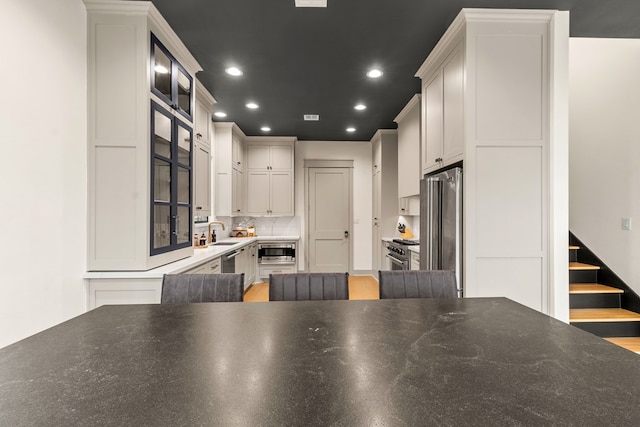 kitchen with a sink, premium appliances, backsplash, and recessed lighting