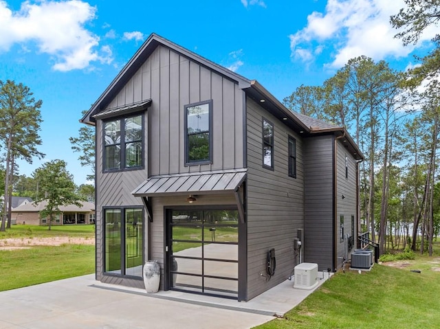exterior space with central air condition unit, a front lawn, board and batten siding, a standing seam roof, and metal roof