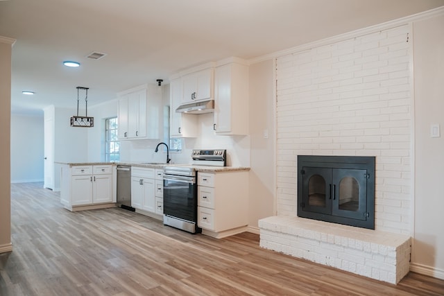 kitchen featuring appliances with stainless steel finishes, light hardwood / wood-style flooring, white cabinets, decorative light fixtures, and sink