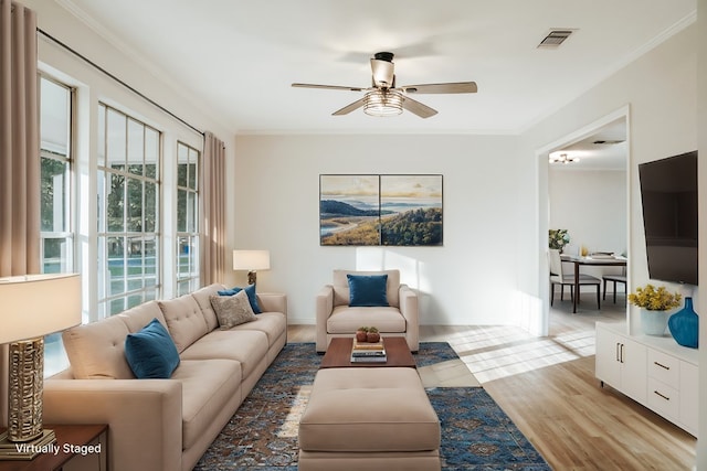 living room featuring ceiling fan, ornamental molding, and light hardwood / wood-style floors