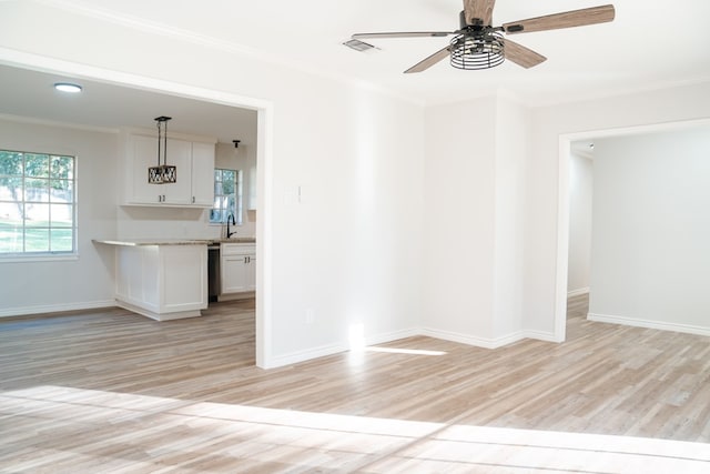 empty room with light wood-type flooring, ornamental molding, sink, and ceiling fan