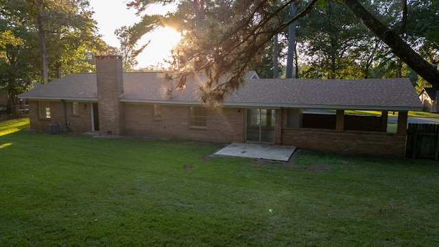 back of property with a lawn, a patio area, and central AC