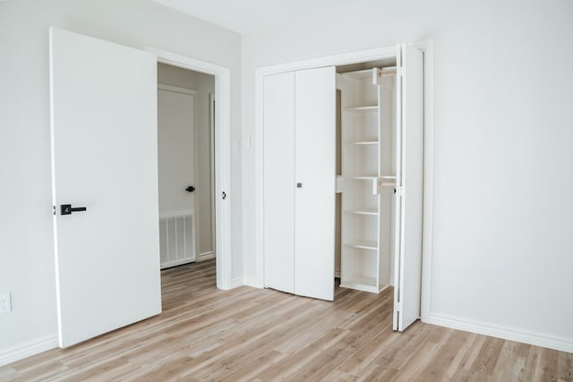 unfurnished bedroom with light wood-type flooring and a closet