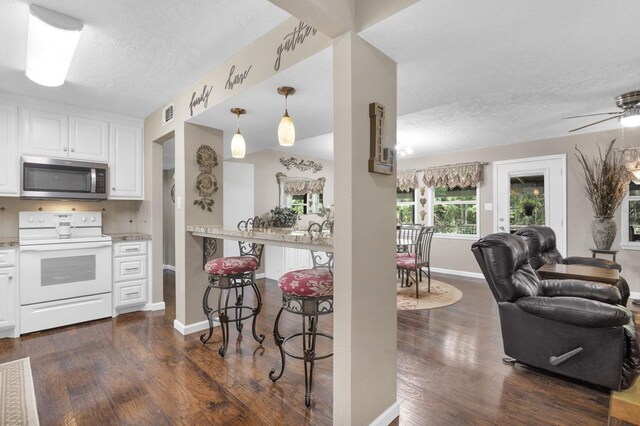 kitchen with pendant lighting, electric range, ceiling fan, dark hardwood / wood-style flooring, and white cabinetry