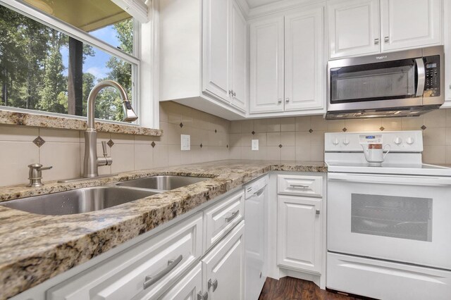 kitchen with tasteful backsplash, light stone counters, white appliances, sink, and white cabinetry