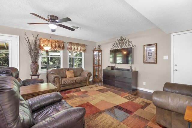 living room with ceiling fan, dark hardwood / wood-style flooring, and a textured ceiling