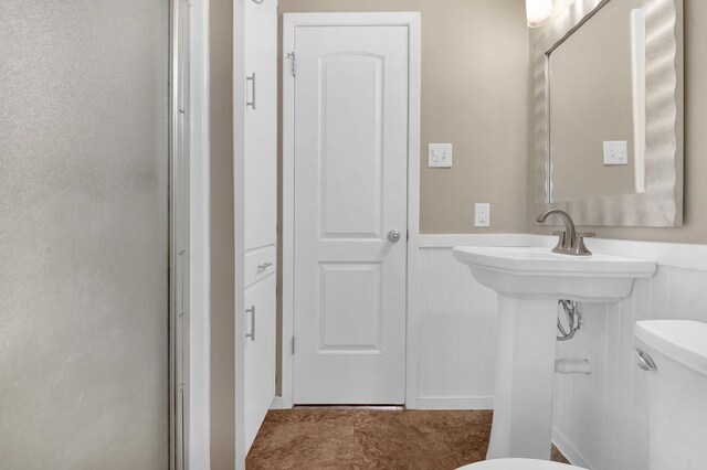 bathroom featuring a shower with door and toilet